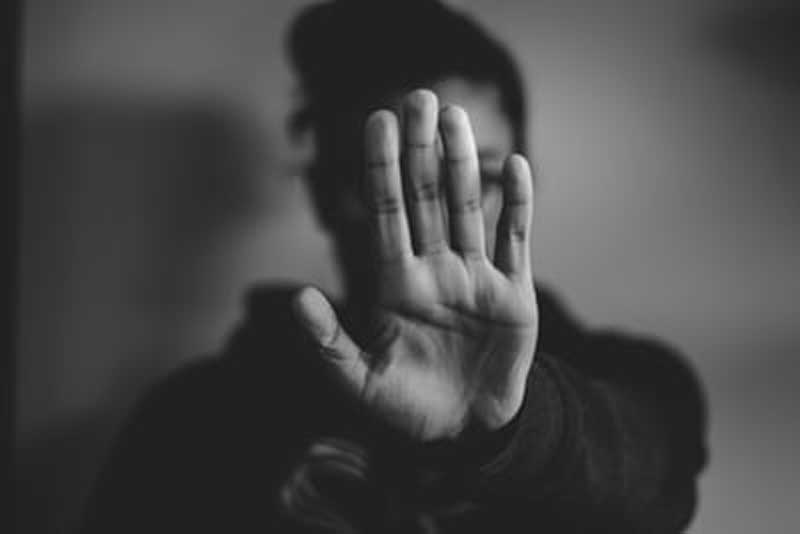 woman wearing sweater with arm outstretched and hand obscuring her face